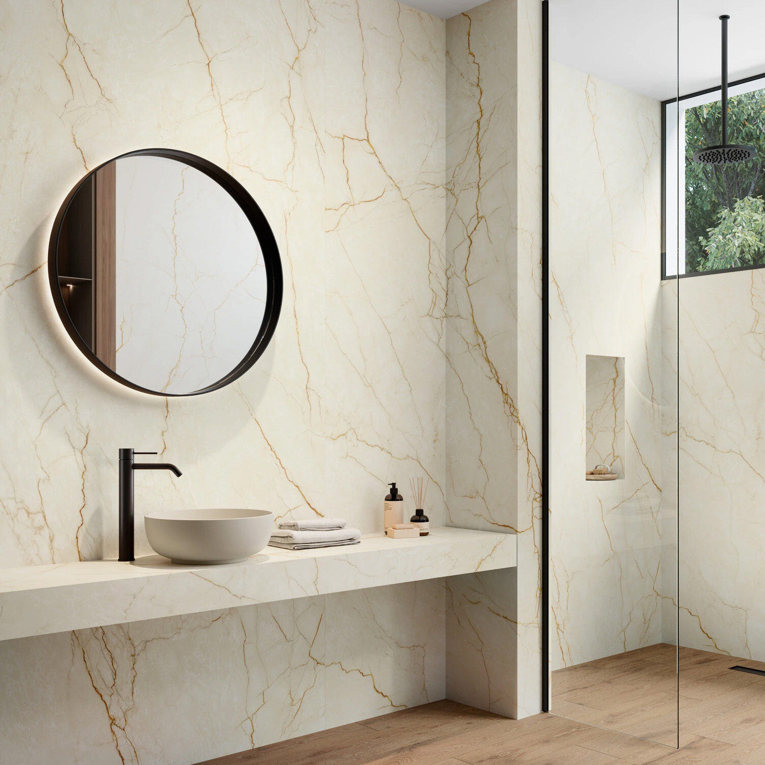 Modern bathroom featuring marble walls, the White Balance vessel sink, a round mirror, black faucet, toiletries, and a walk-in shower with a rainfall showerhead. Natural light filters in through a window with views of greenery outside.
