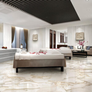 Experience the luxurious Bernini Oro spa room, featuring elegant marble floors, two massage tables adorned with towels and rose petals, graceful curtains, fresh flower arrangements in vases, decorative wall art, and a softly lit ambiance perfect for relaxation.