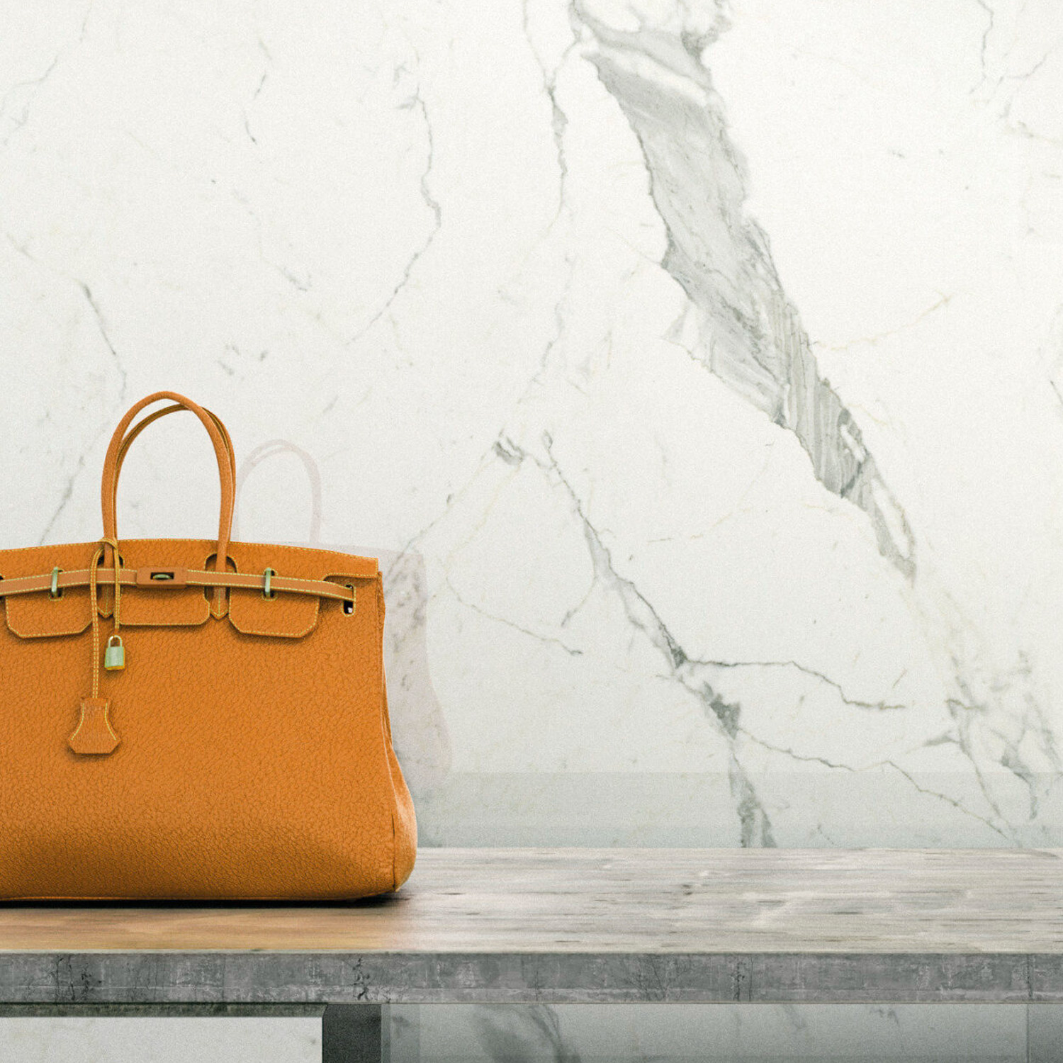 A Statuarietto orange leather handbag rests on a gray surface in front of a white marble wall.
