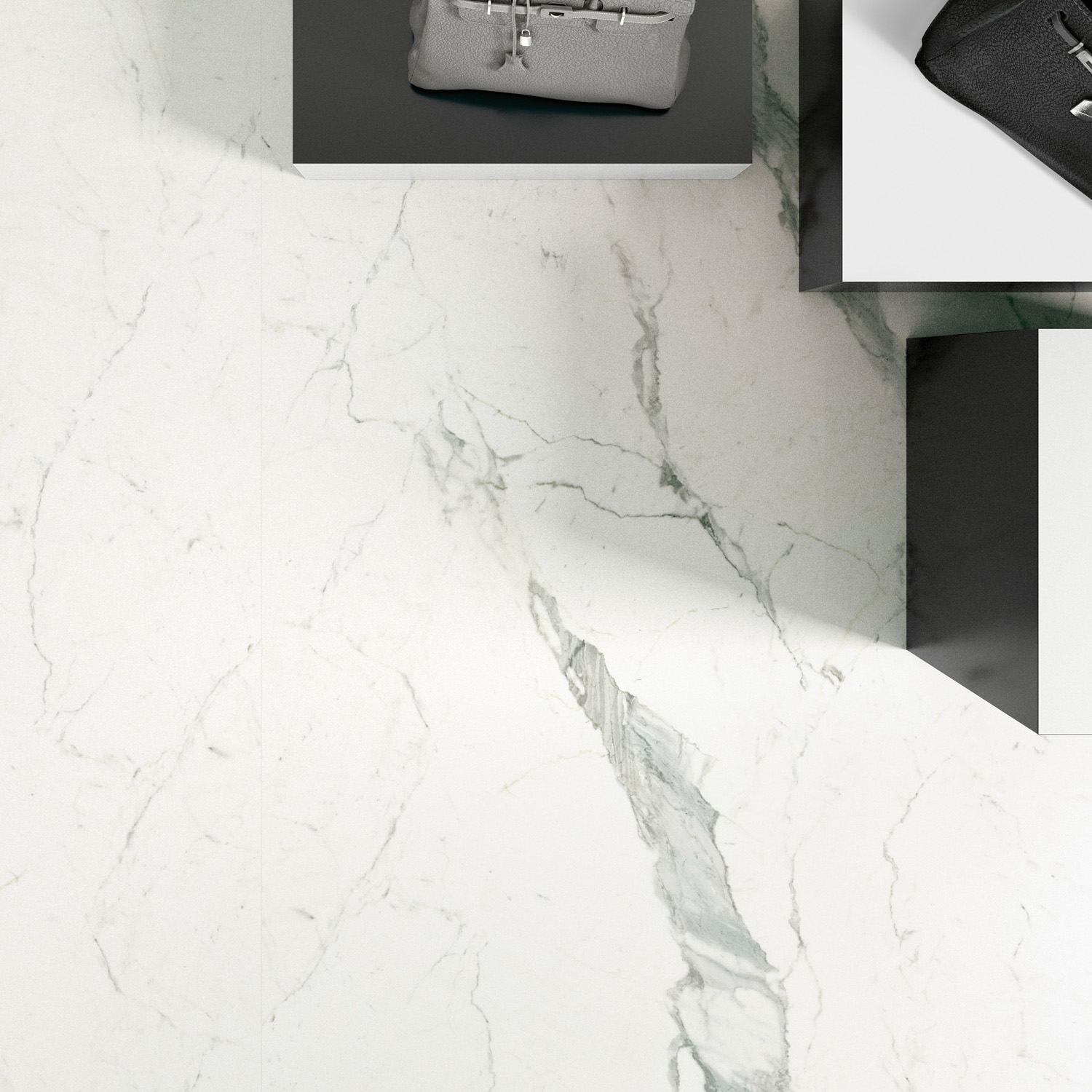 Two handbags, one beige and one black, are displayed on white and black platforms over a Statuarietto marble surface with gray veins. The bags are positioned in the upper right corner of the image.